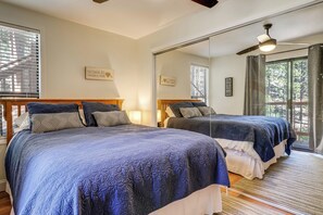 Une chambre avec deux lits, un grand miroir et un ventilateur de plafond.