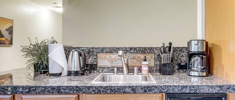A modern kitchen with granite countertops, stainless steel appliances, and wooden cabinetry.