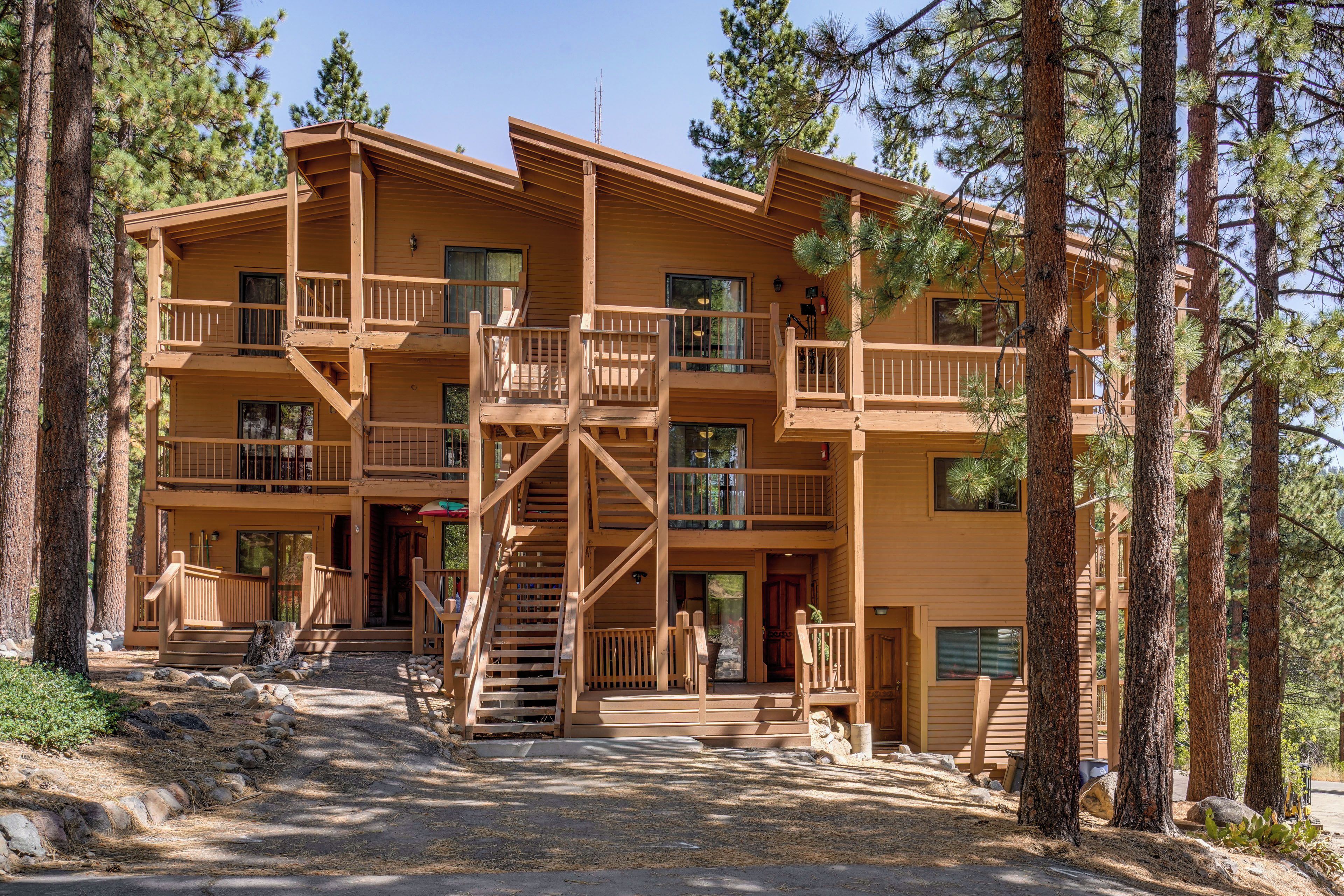 A multi-story wooden building with balconies, a central staircase, and a surrounding forest.