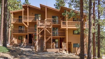 Un bâtiment en bois à plusieurs étages, doté de balcons, d’un escalier central et entouré d’une forêt.