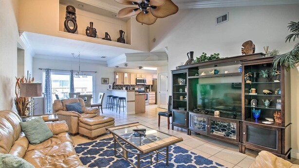 A spacious living room with a leather sofa, a glass coffee table, and a decorative cabinet. - South Padre Island Condo w/ Pool Access & Balcony! (South Padre Island)