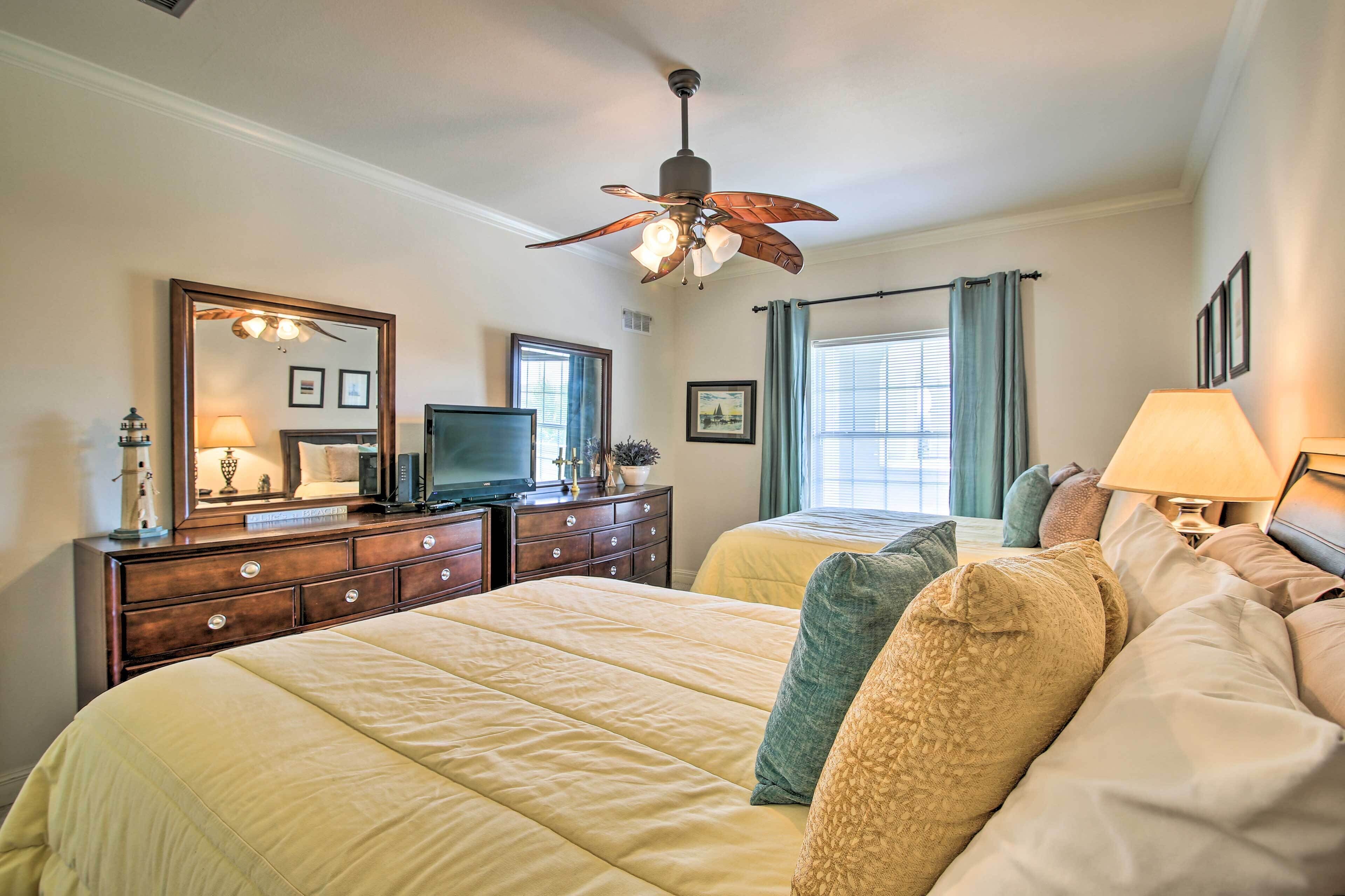 A hotel room with a large bed, a dresser, a television, and a ceiling fan.