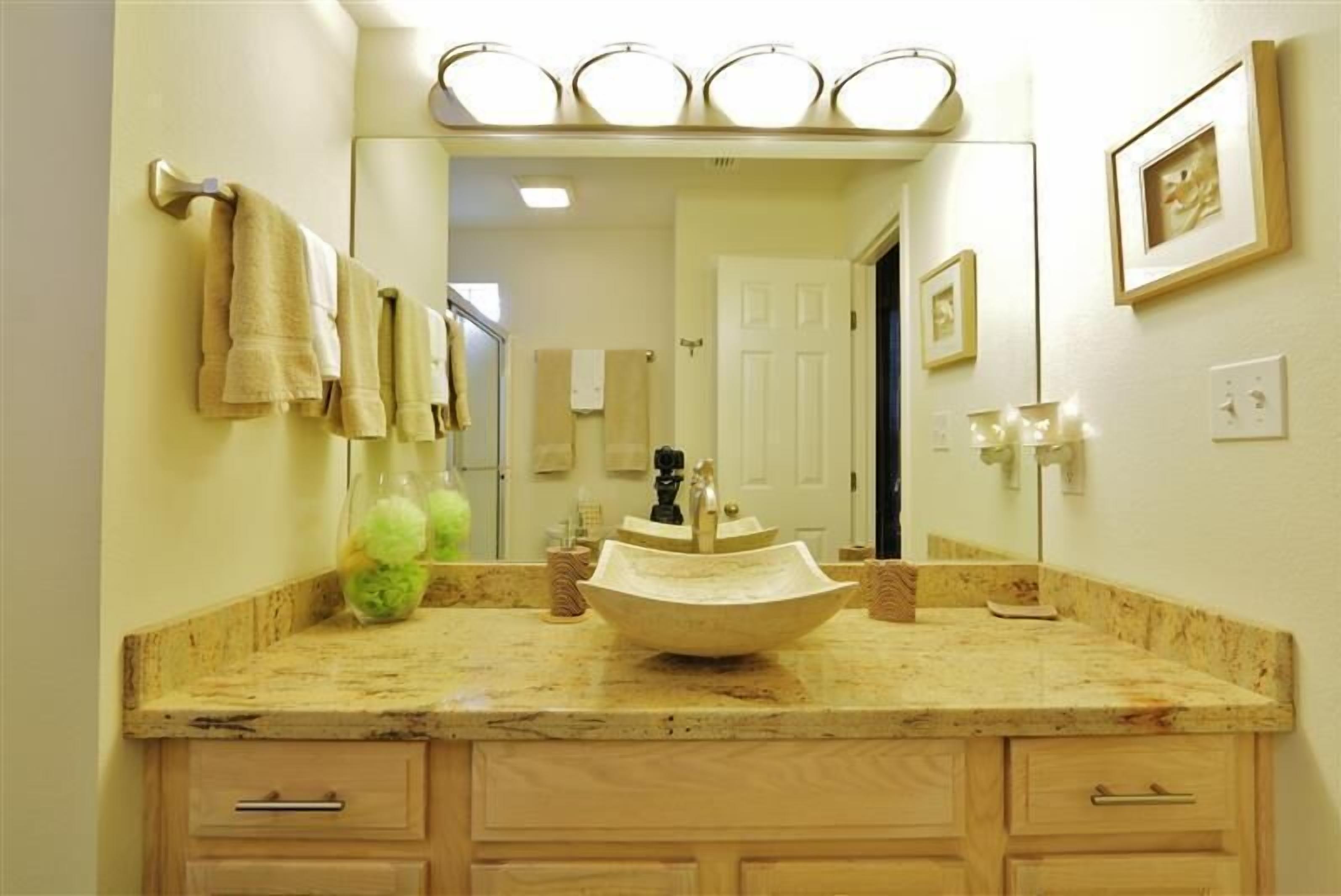 Une salle de bain dotée d’un grand miroir, d’un lavabo sur colonne et de meubles en bois.