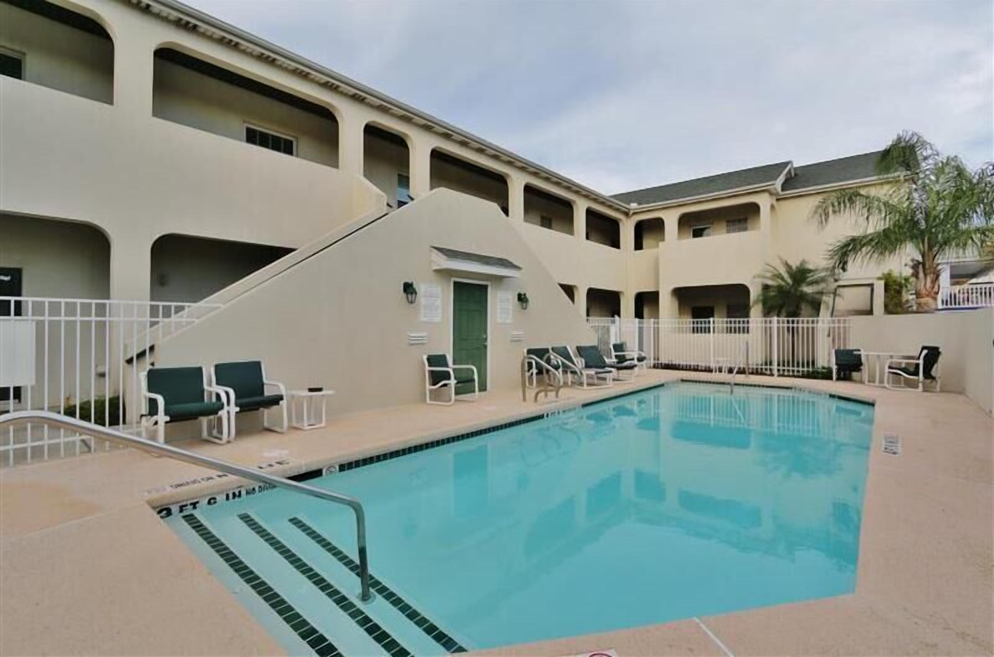 A swimming pool with lounge chairs and a staircase leading to an upper level.