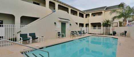 A swimming pool with lounge chairs and a staircase leading to an upper level.