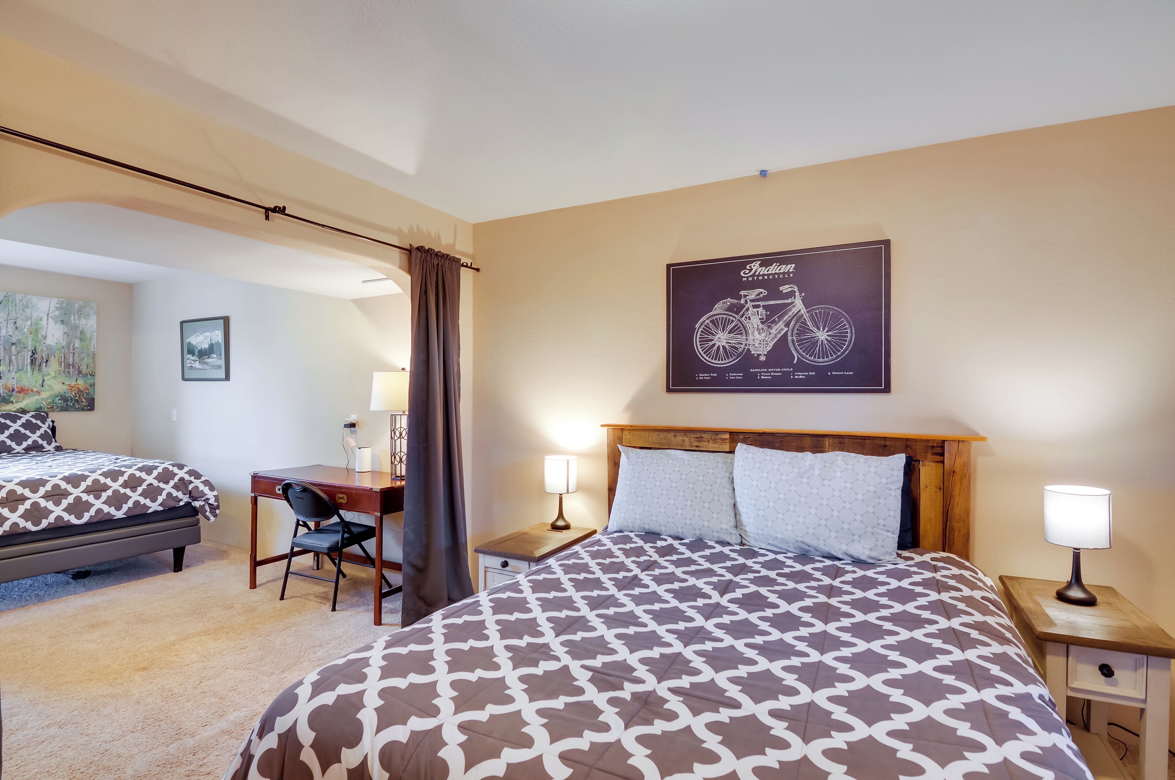 A hotel room with two beds, a desk, and a bicycle-themed poster on the wall.
