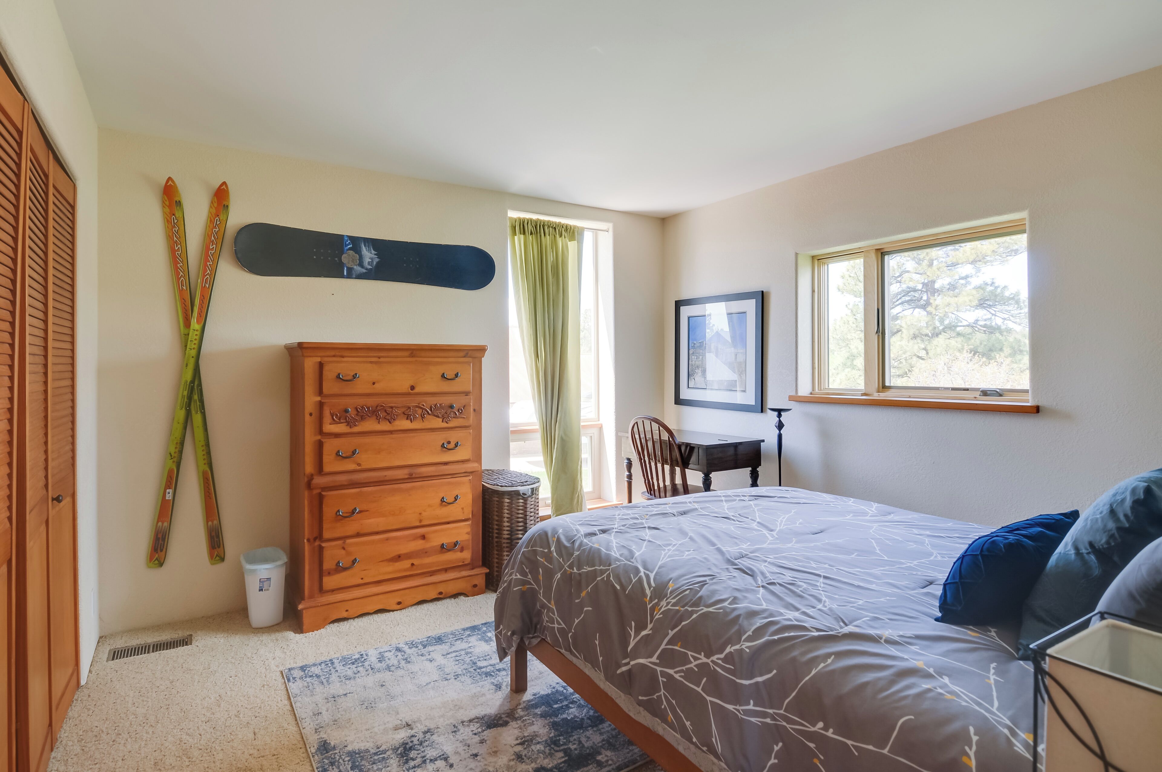 Une chambre à coucher avec un lit, une commode, des skis et une fenêtre.