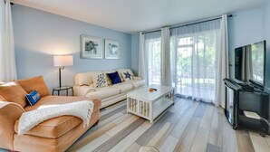 Un salon avec un canapé, une table basse, un téléviseur et des œuvres d’art accrochées au mur.