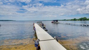 A wooden pier extending into a calm lake with boats docked at the end. - Bright Shawano Lake Oasis - Walk to Boat Launch! (Cecil)