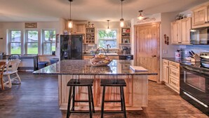A spacious kitchen with a large island, wooden cabinets, and pendant lighting. - Bright Shawano Lake Oasis - Walk to Boat Launch! (Cecil)