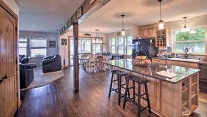 A spacious kitchen with a central island, wooden cabinets, and a large window providing natural light. - Bright Shawano Lake Oasis - Walk to Boat Launch! (Cecil)