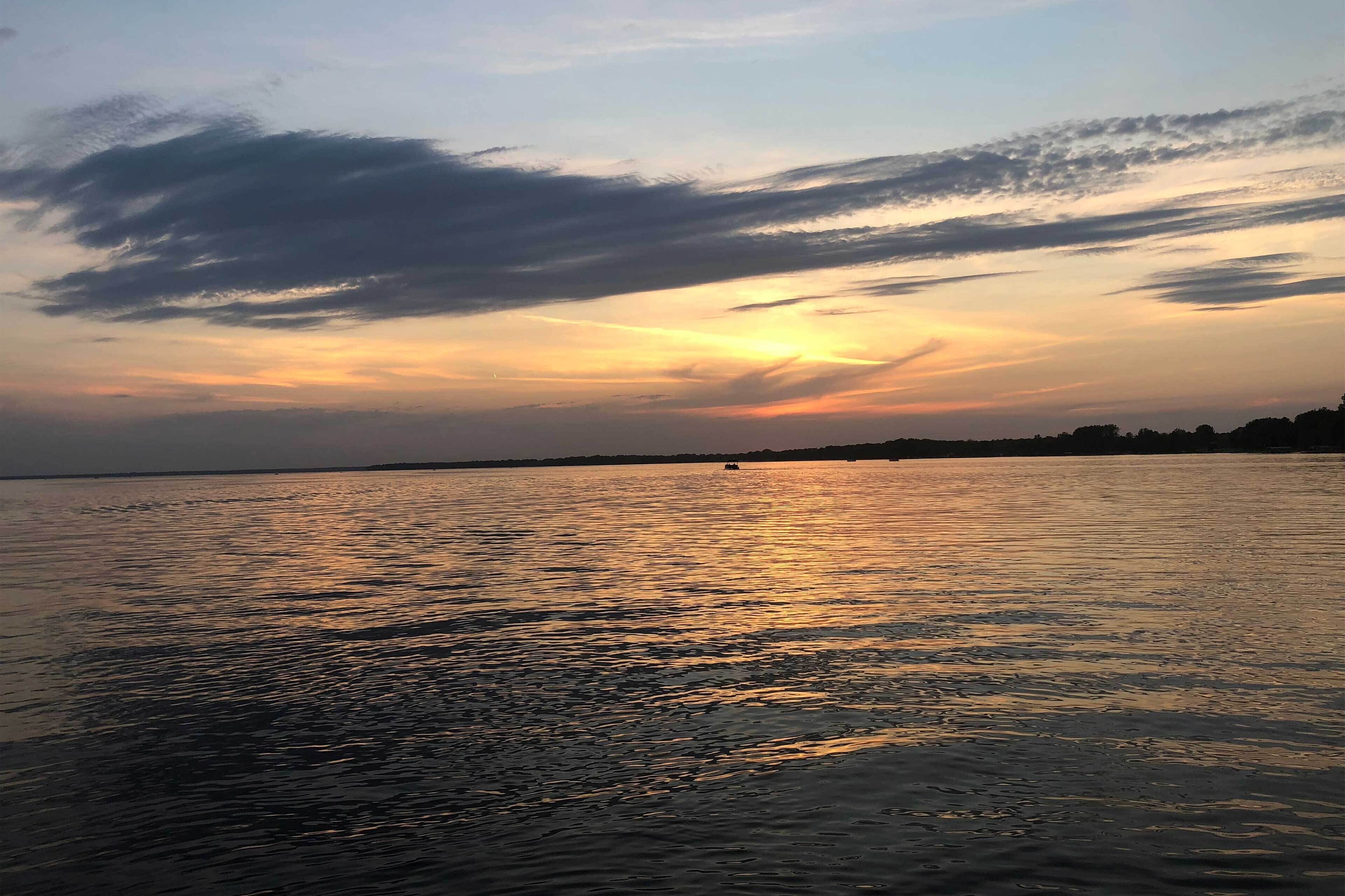A calm body of water reflecting the sky during sunset.