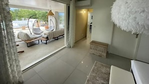 A modern interior with a glass door leading to an outdoor seating area, a fluffy white ceiling ornament, and a tiled floor. - Le Petit Millenium Avec SPA et Piscine (Saint-Alban-Auriolles)