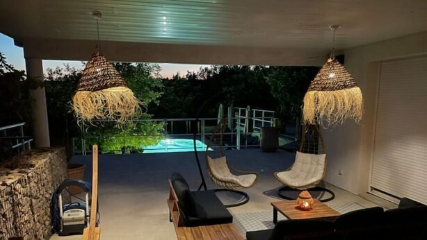 An outdoor seating area with wicker chairs and a wooden table, overlooking a swimming pool. - Le Petit Millenium Avec SPA et Piscine (Saint-Alban-Auriolles)
