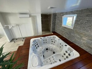 Bathroom features a bathtub, stone wall, and window.