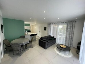 Relax in this inviting living space with a dining table, sofa, and coffee table, plus a kitchen area with microwave and sink.