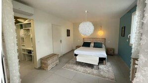 A bedroom with a bed, bedside tables, a hanging light fixture, and a wardrobe. - Le Petit Millenium Avec SPA et Piscine (Saint-Alban-Auriolles)