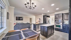 A modern kitchen with dark cabinetry, stainless steel appliances, and a central island. - Immaculate 'woodland View' Retreat w/ Hot Tub (Tulsa)
