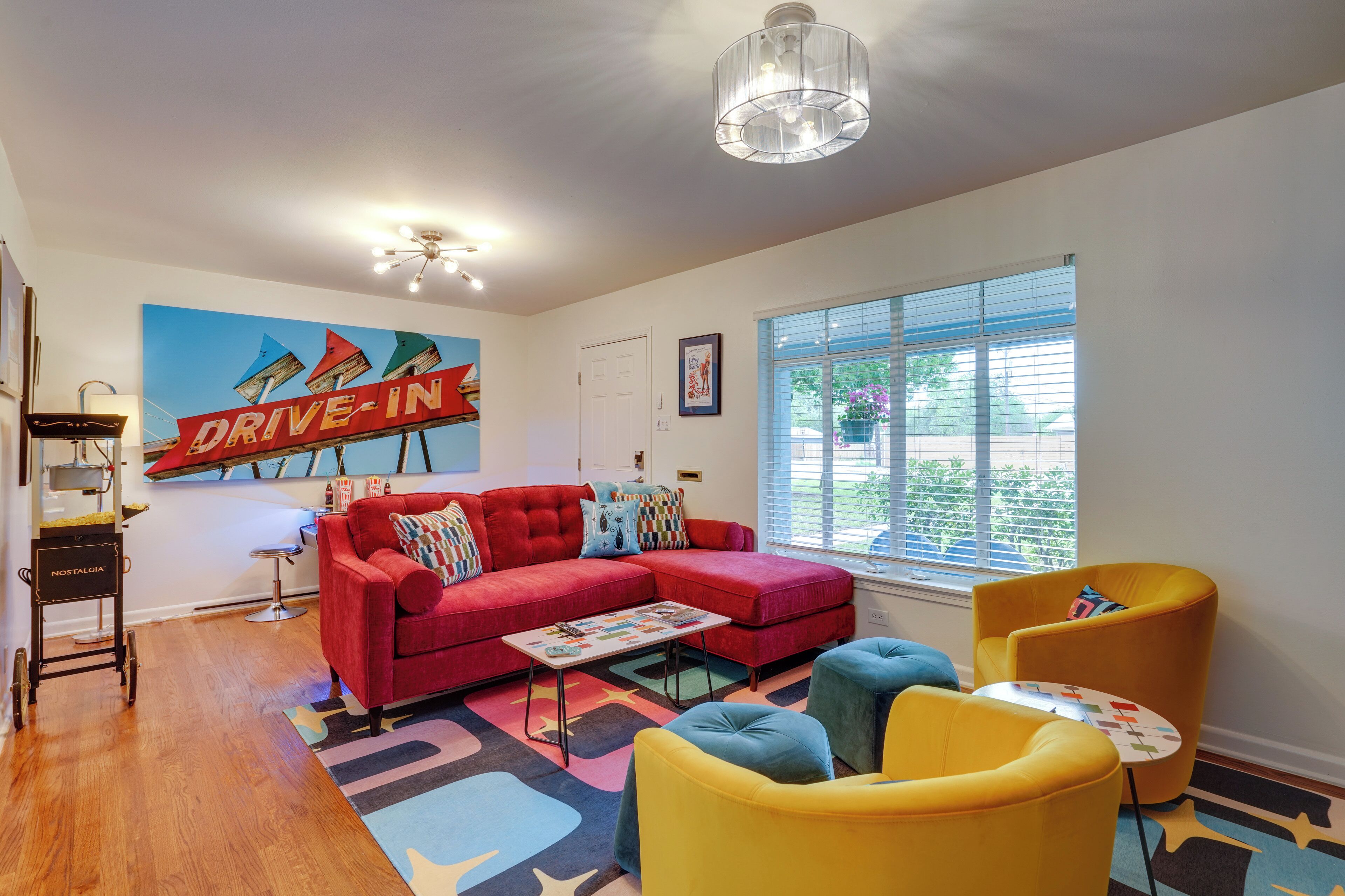 Una sala de estar moderna con un sofá seccional rojo, sillones amarillos y una alfombra colorida.
