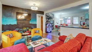 Ein modernes Wohnzimmer mit lebendigen Möbeln, einem Retro-Jukebox und einer durch einen offenen Durchgang einsehbaren Küche.