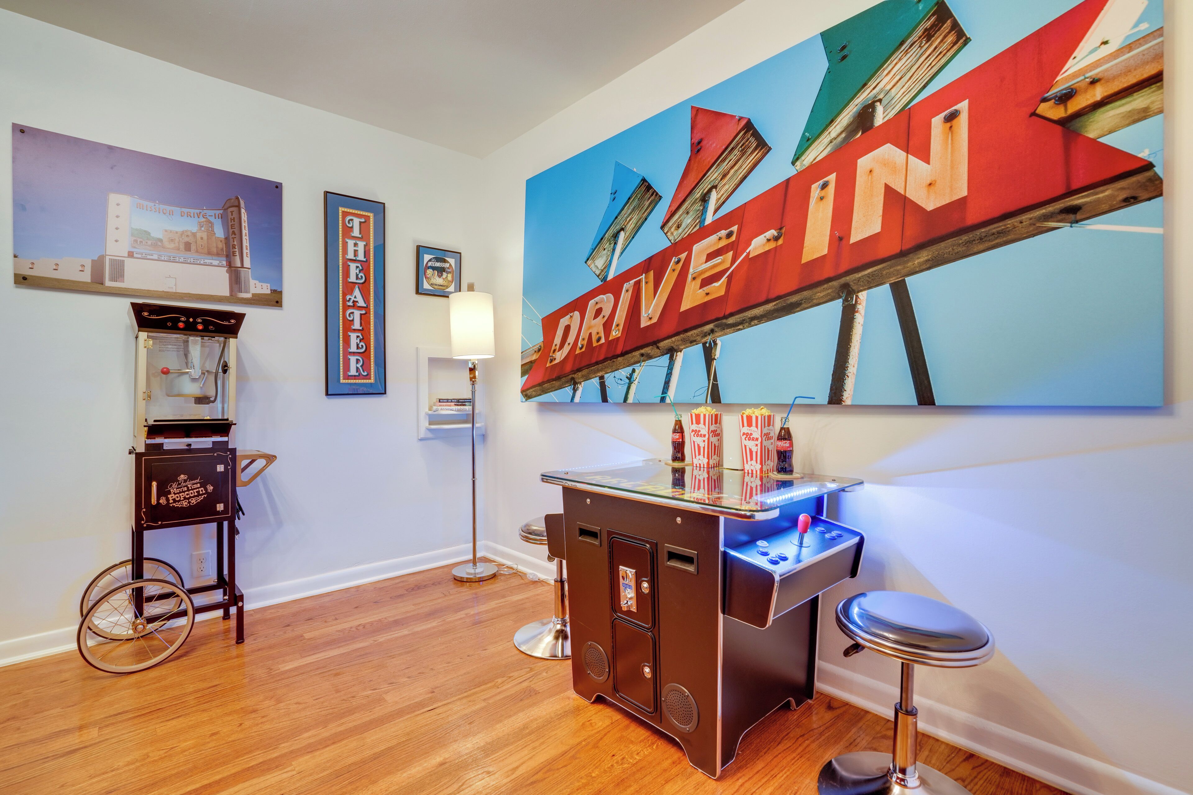 A bar area with a vintage jukebox, a neon sign, and a large painting of buildings.