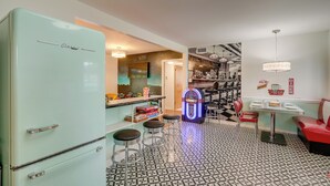 Eine Küche im Retro-Stil mit einem mintgrünen Kühlschrank, Barhocker, einer Jukebox und einer Kaffeestation.