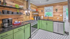 A kitchen with green cabinets, a stainless steel range, and a dishwasher.