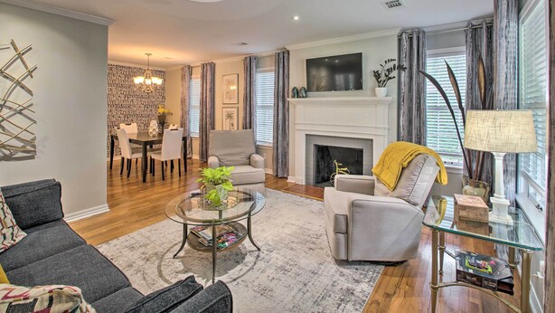 A modern living room with a fireplace, a dining area, and a seating area with a sofa and armchairs.
