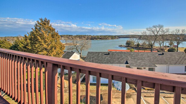 Vista desde un balcón sobre un lago, con casas y árboles al fondo.