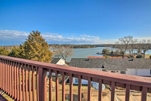 Une vue depuis un balcon donnant sur un lac, avec des maisons et des arbres en arrière-plan.