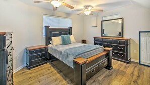 Un dormitorio con cama, dos mesitas de noche, cómoda y un ventilador de techo, además de un espejo.