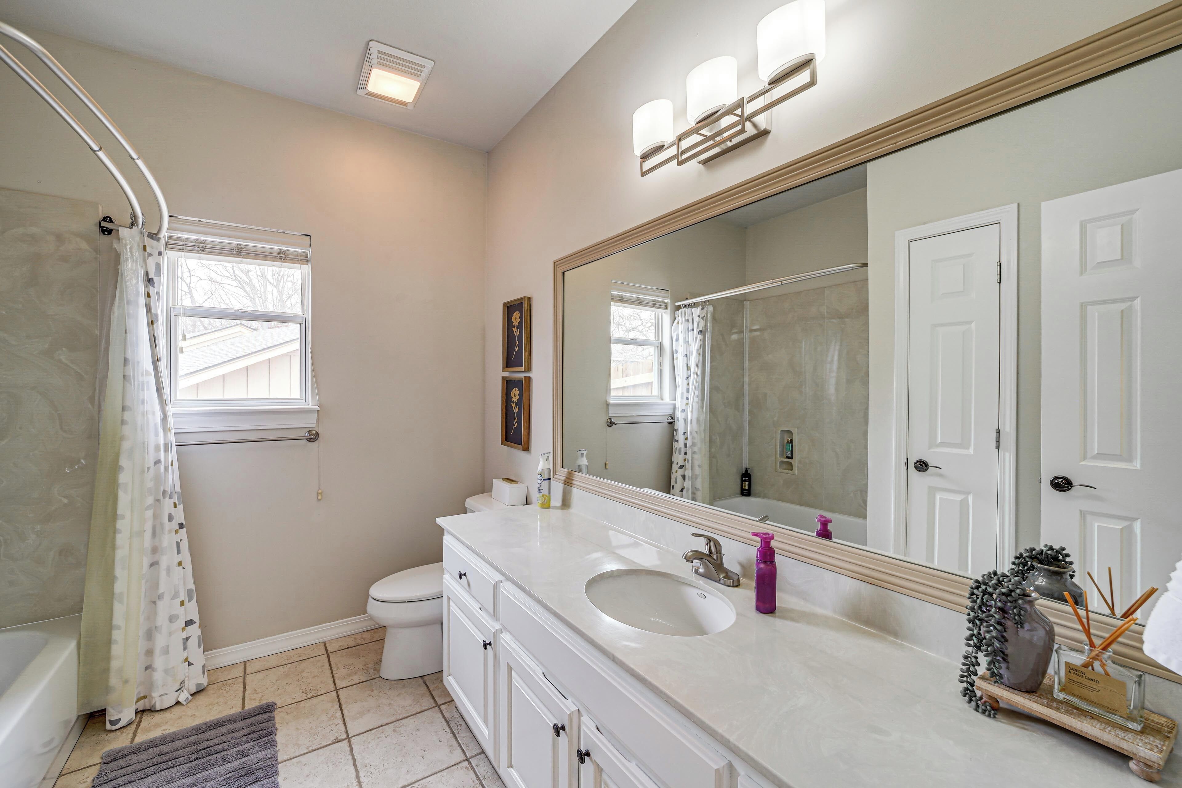 Une salle de bain avec une baignoire, des toilettes, un lavabo et un grand miroir.