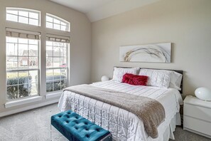 Ein Schlafzimmer mit einem großen Bett, einer Bank, einem Nachttisch und einem Fenster mit Blick nach draußen.