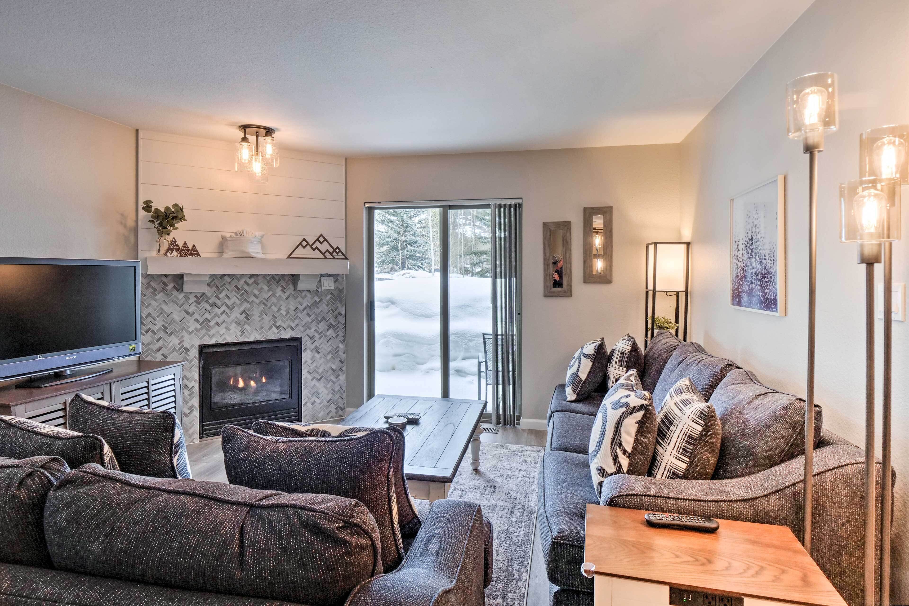 A modern living room with a fireplace, a flat-screen TV, and a sofa set.