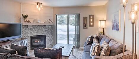 A modern living room with a fireplace, a flat-screen TV, and a sofa set.