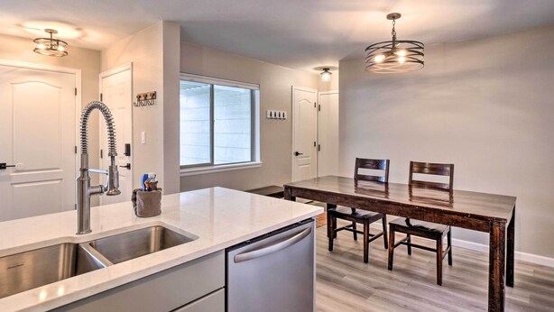 A modern kitchen with a stainless steel sink, a dishwasher, and a wooden dining table with chairs. - Frisco Condo w/ 2 Hot Tubs: Steps to Lake Dillon (Frisco)