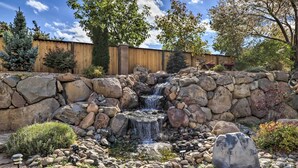 A garden with a small waterfall, surrounded by rocks and plants. - Large Yard + Hot Tub: Reno Retreat! (Reno)