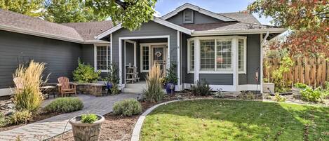 A residential house with a covered patio, a stone pathway, and a well-maintained lawn.