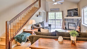A spacious living room with a wooden staircase, a fireplace, a sofa, a coffee table, and a television. - Breck Condo w/ Hot Tub Access: 6 Mi to Ski Resort! (Breckenridge)