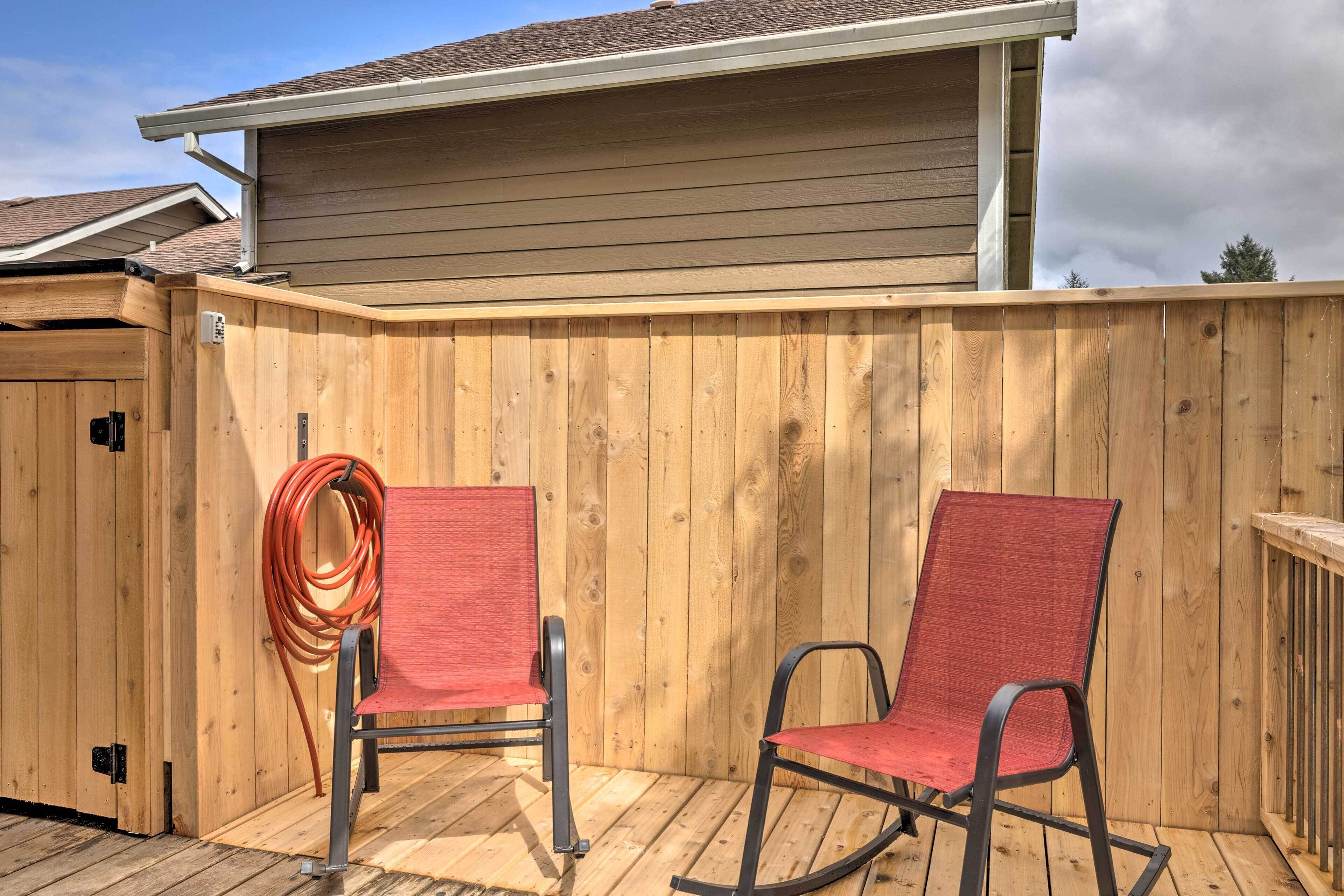 A wooden deck with two rocking chairs and a hose coiled on the floor.