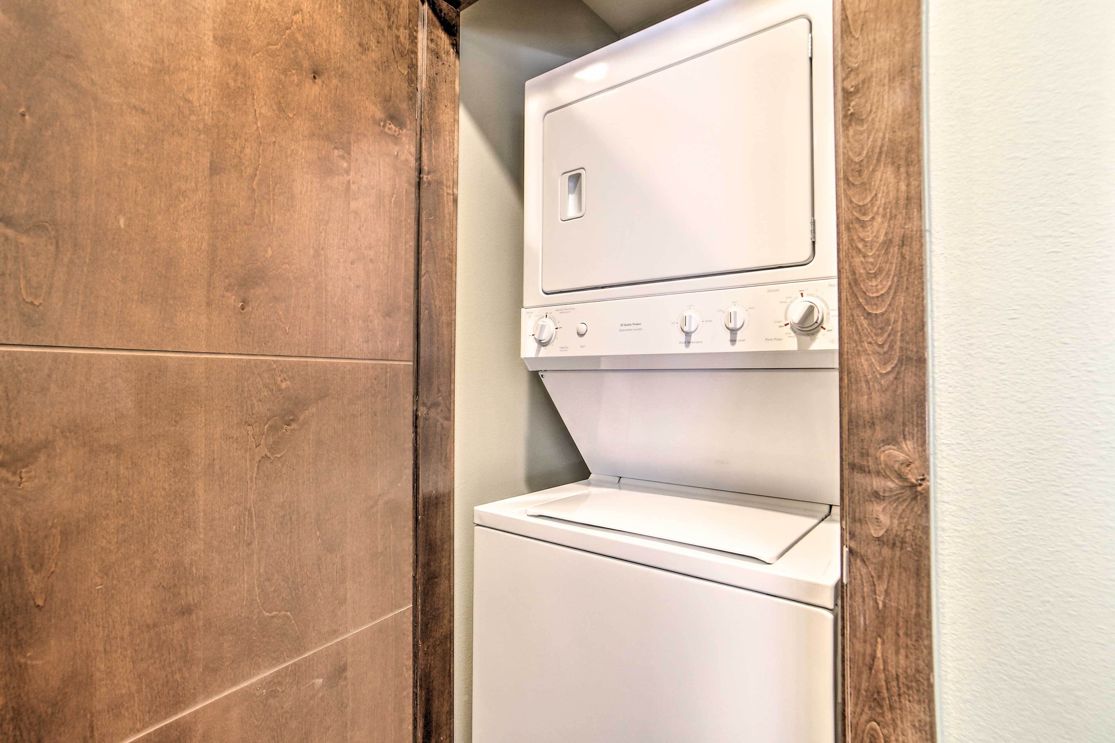 A compact, white, wall-mounted washer and dryer unit with a wooden frame.