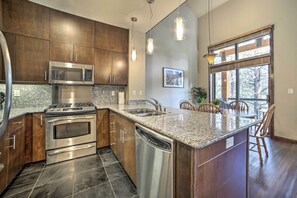 A modern kitchen with stainless steel appliances, granite countertops, and a large island with bar stools. - Modern Mammoth Lakes Condo: Ski, Hike, & More! (Mammoth Lakes)