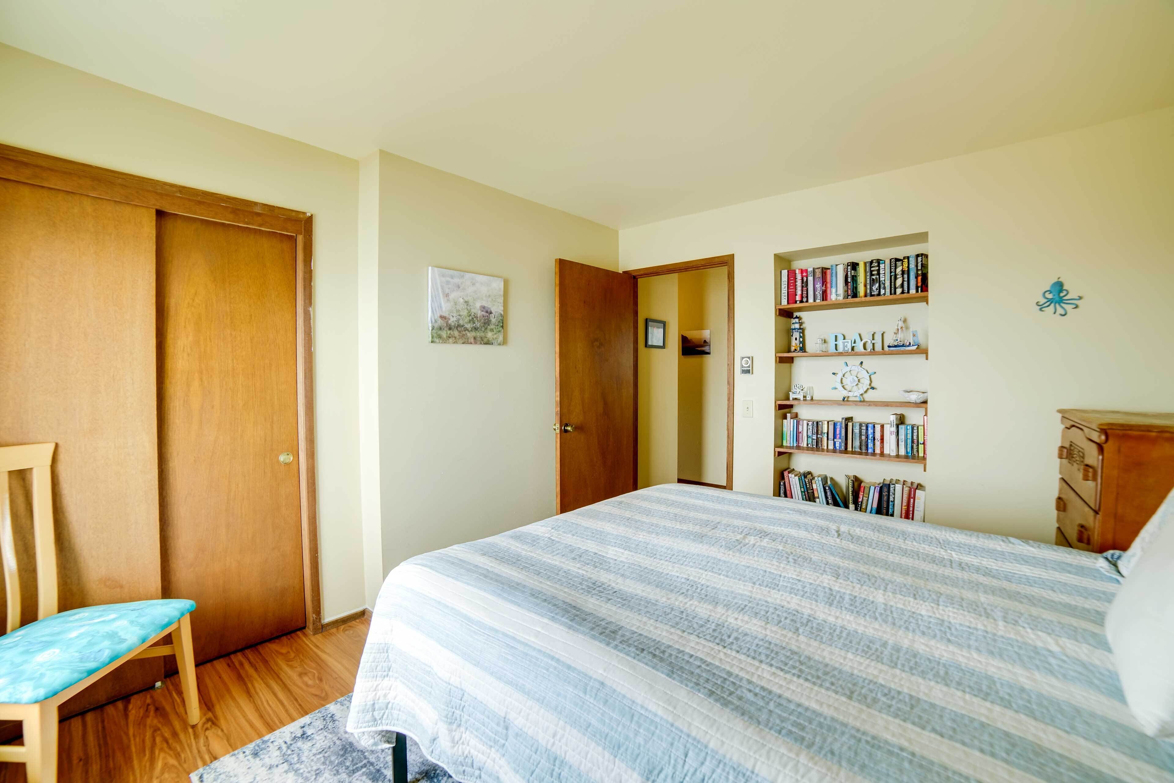 A bedroom with a bed, a chair, a bookshelf, and a wardrobe.