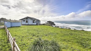 A coastal house with a grassy lawn and a wooden fence.