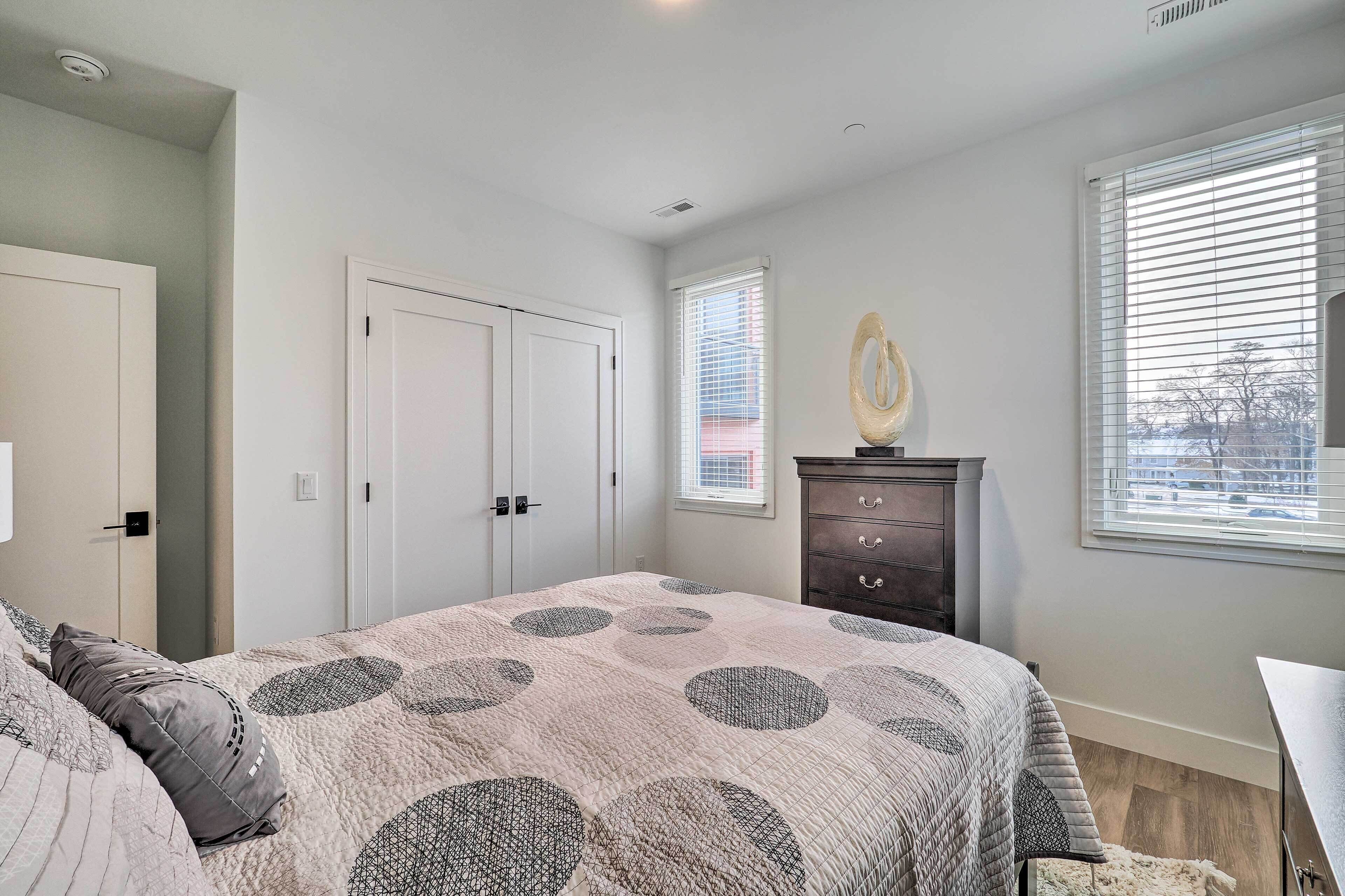 A bedroom with a bed, a dresser, a window, and a door.