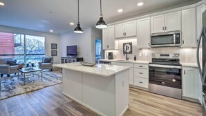 A modern kitchen with white cabinets, stainless steel appliances, and pendant lighting. - Downtown Traverse City Condo: 32 Mi to Ski Slopes! (Traverse City)