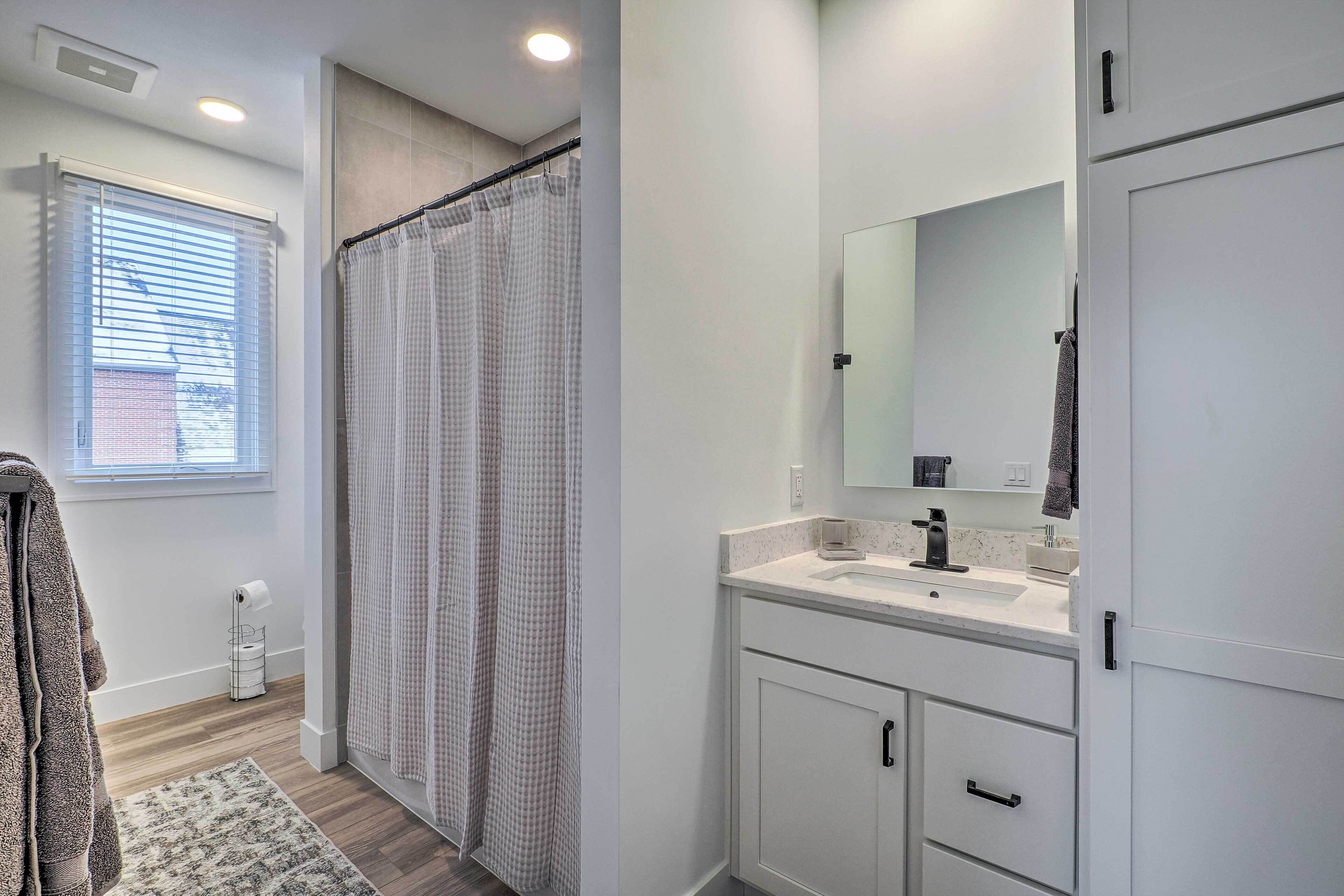 Un baño moderno con ducha, lavamanos y espejo.