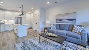 A modern living room with a grey sofa, a coffee table, and a painting on the wall. - Downtown Traverse City Condo: 32 Mi to Ski Slopes! (Traverse City)