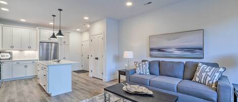 A modern living room with a grey sofa, a coffee table, and a painting on the wall.