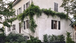 A two-story building with a stone-paved courtyard, multiple windows with shutters, and a chimney. - Sessius 1622 (Cessy)